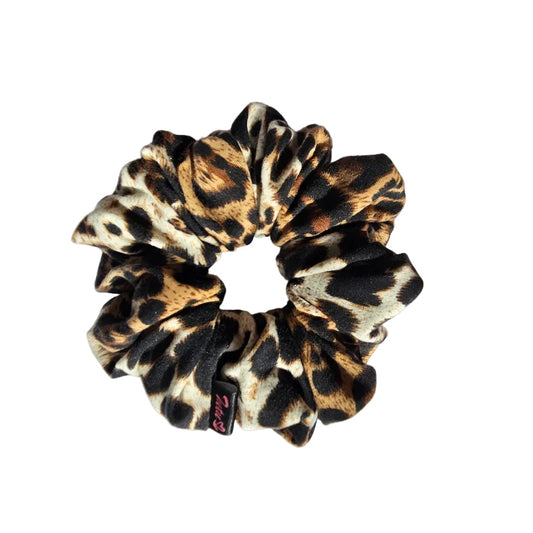 A leopard print fabric scrunchie with black, brown, and beige spots, resting on a white background