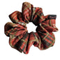 A fabric hair scrunchie with a orange, brown, and beige plaid pattern on a white background. A small black brand tag reading 'Tutu22' is visible on the right side.