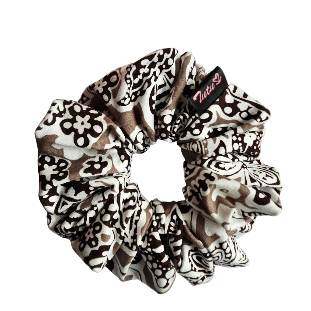 A fabric hair scrunchie with a brown, black, and white abstract pattern, featuring a small black brand tag that reads 'Tutu22'.